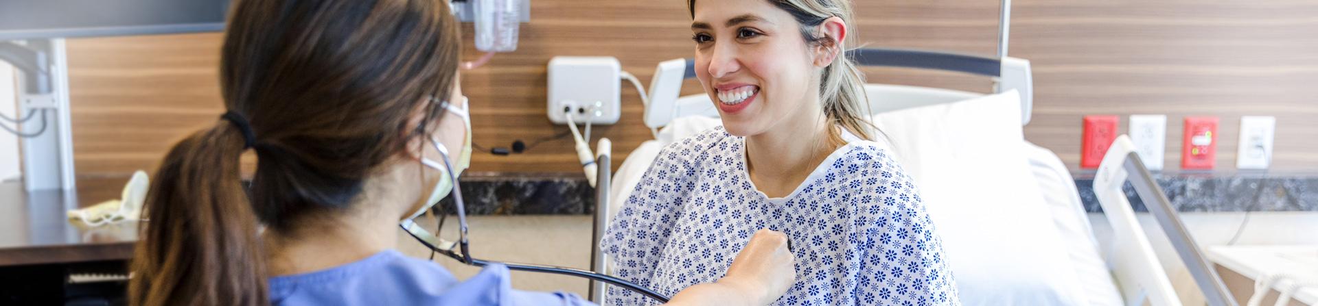 A healthcare provider placing a stethoscope on a female patient's chest.
