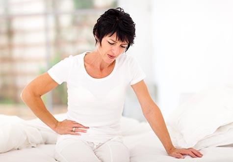 Woman in white shirt clutches side in pain