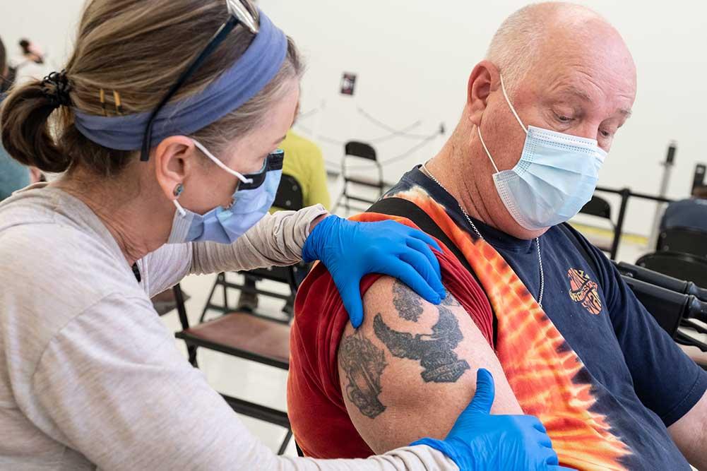 John Luderman receives the 100,000th COVID-19 vaccine dose provided by UVA Health.