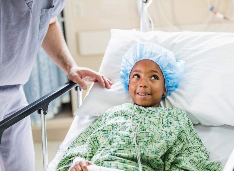 Child in surgical gown and cap lays in hospital bed