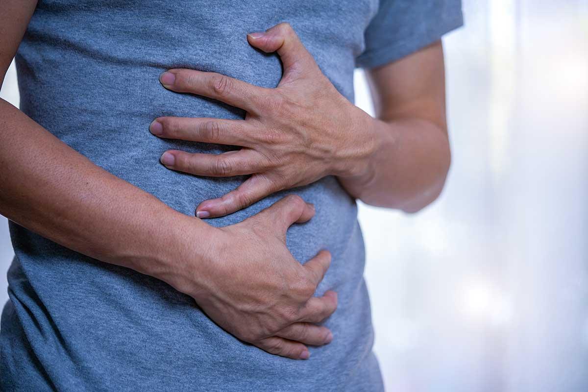Man clutches stomach, in pain from gastric cancer symptoms
