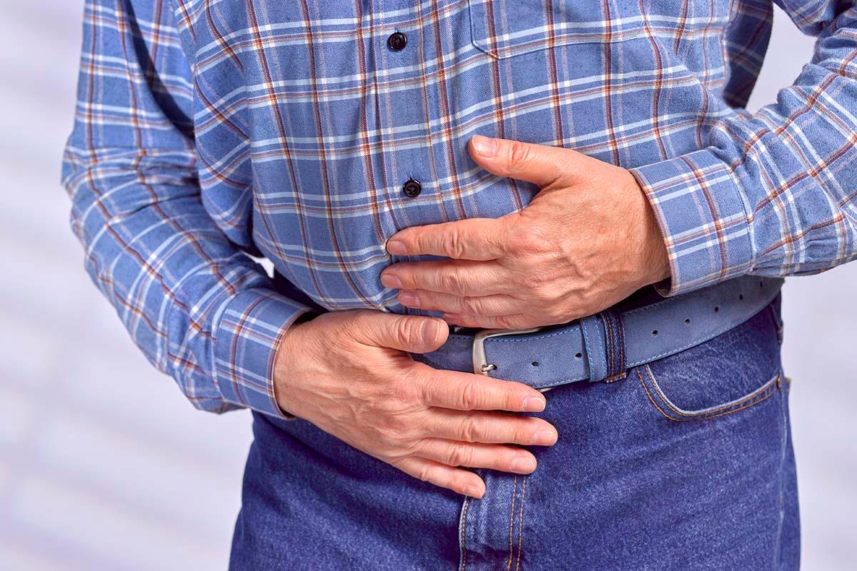 A man holds his abdominal area with his hands in pain