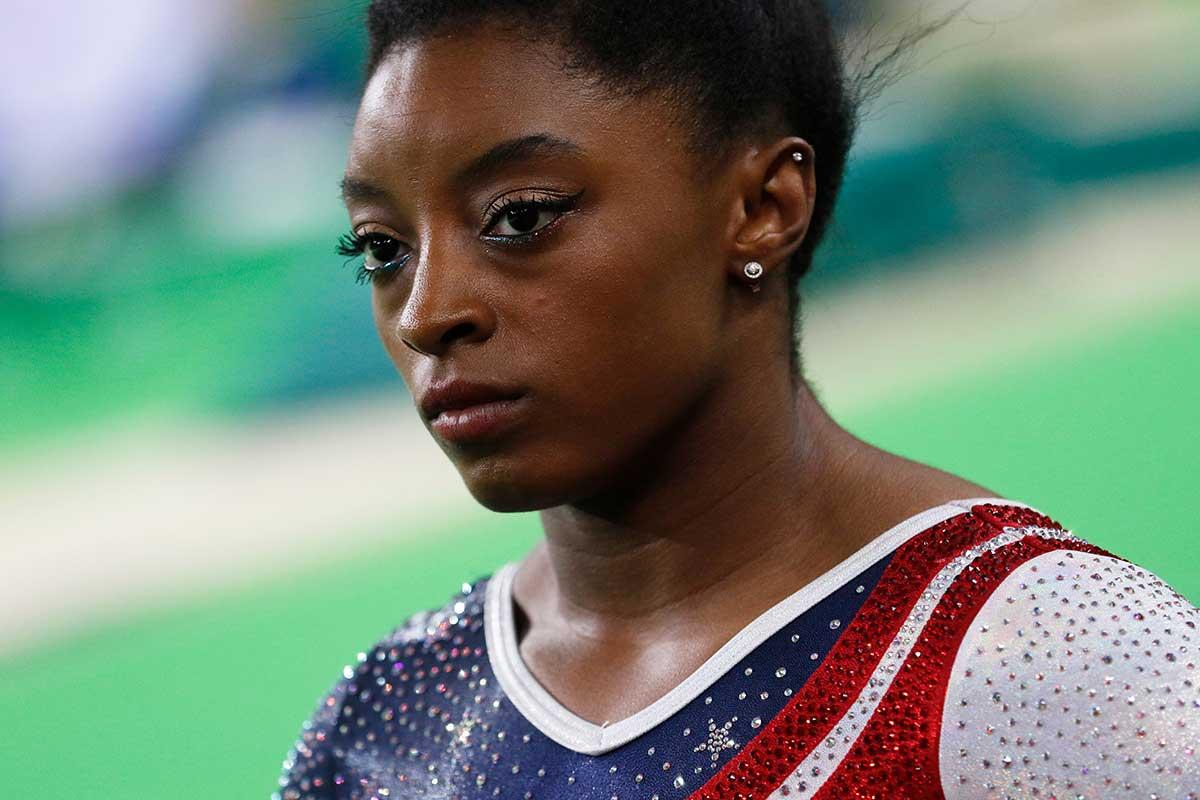 Simone Biles, world-famous gymnast, looks contemplative during a meet