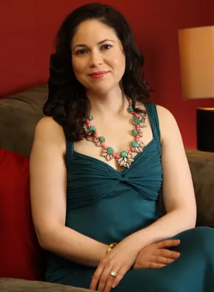 Young healthy looking woman sits in chair and smiles