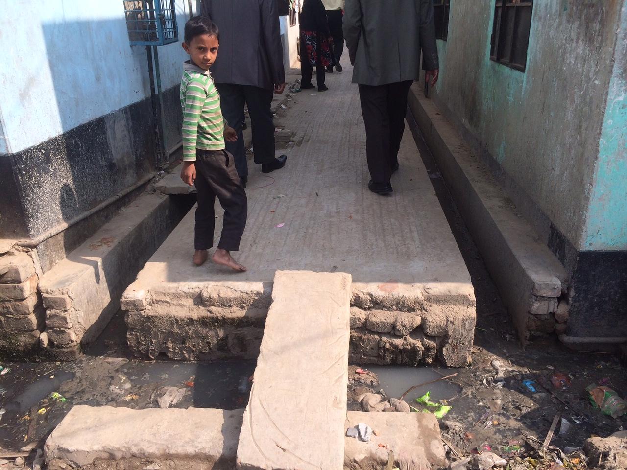 A child walks near an open sewer in Bangladesh.