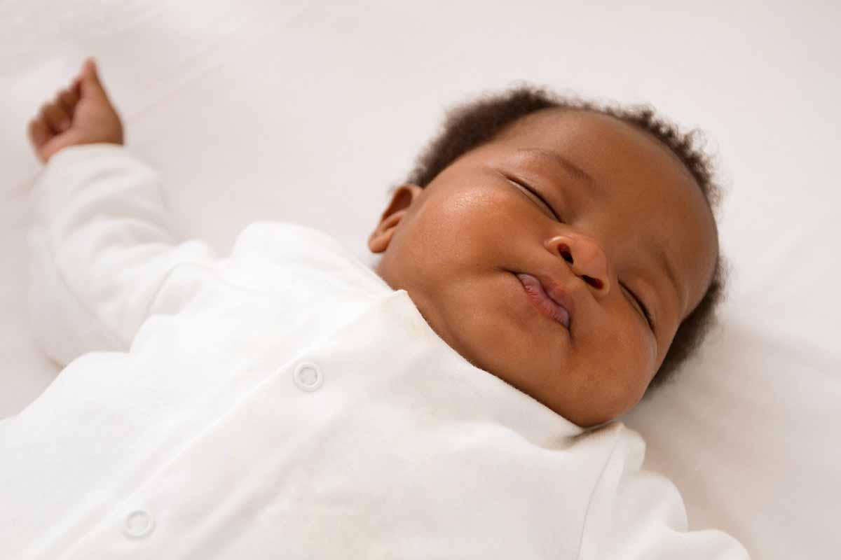 Happy black baby sleeping comfortably on back