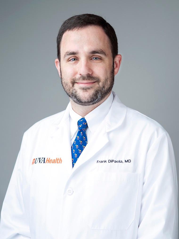 A headshot of Frank DiPaola smiling while wearing a white coat