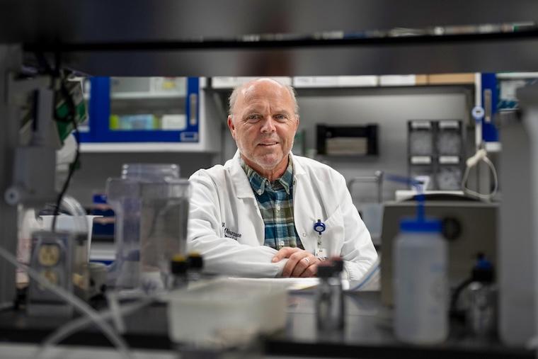 Researcher Harald Sontheimer, PhD, in white coat poses and smiles in his lab