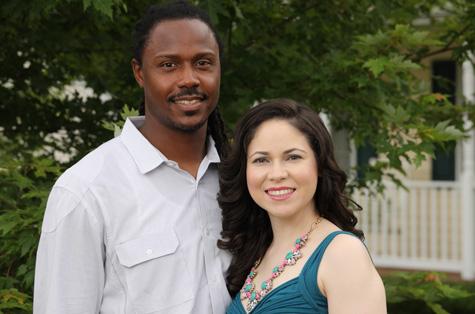A young couple (Leslie Waller and husband, Quincy) smiles at the camera on a pretty sunny day