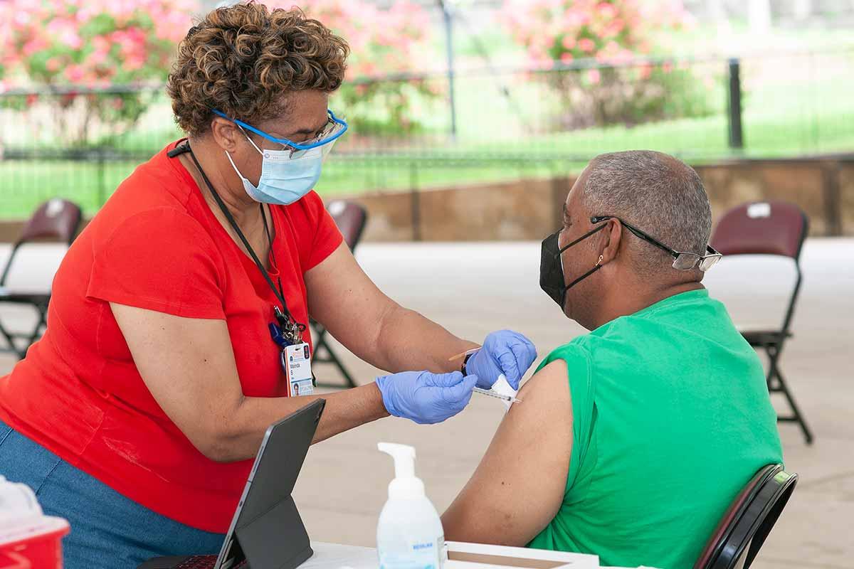 vaccinator giving person COVID vaccine