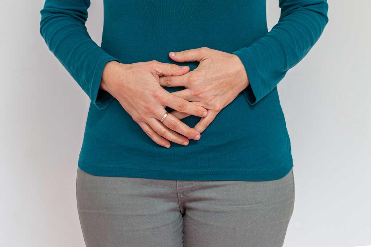 Woman stands with hands clasped over belly