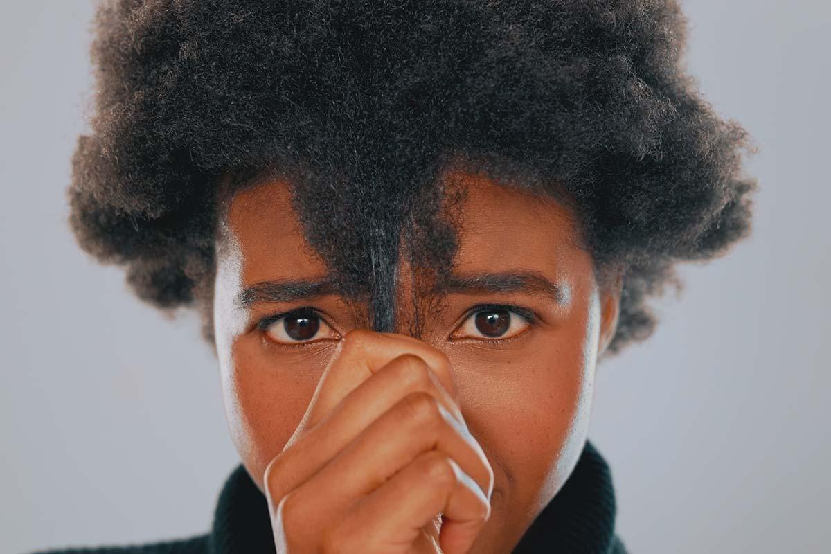 Black woman pulls down strand of natural hair