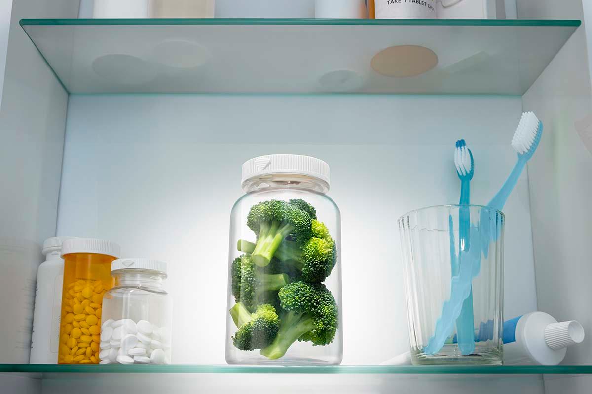 Pieces of broccoli in a pill bottle in a medicine cabinet.