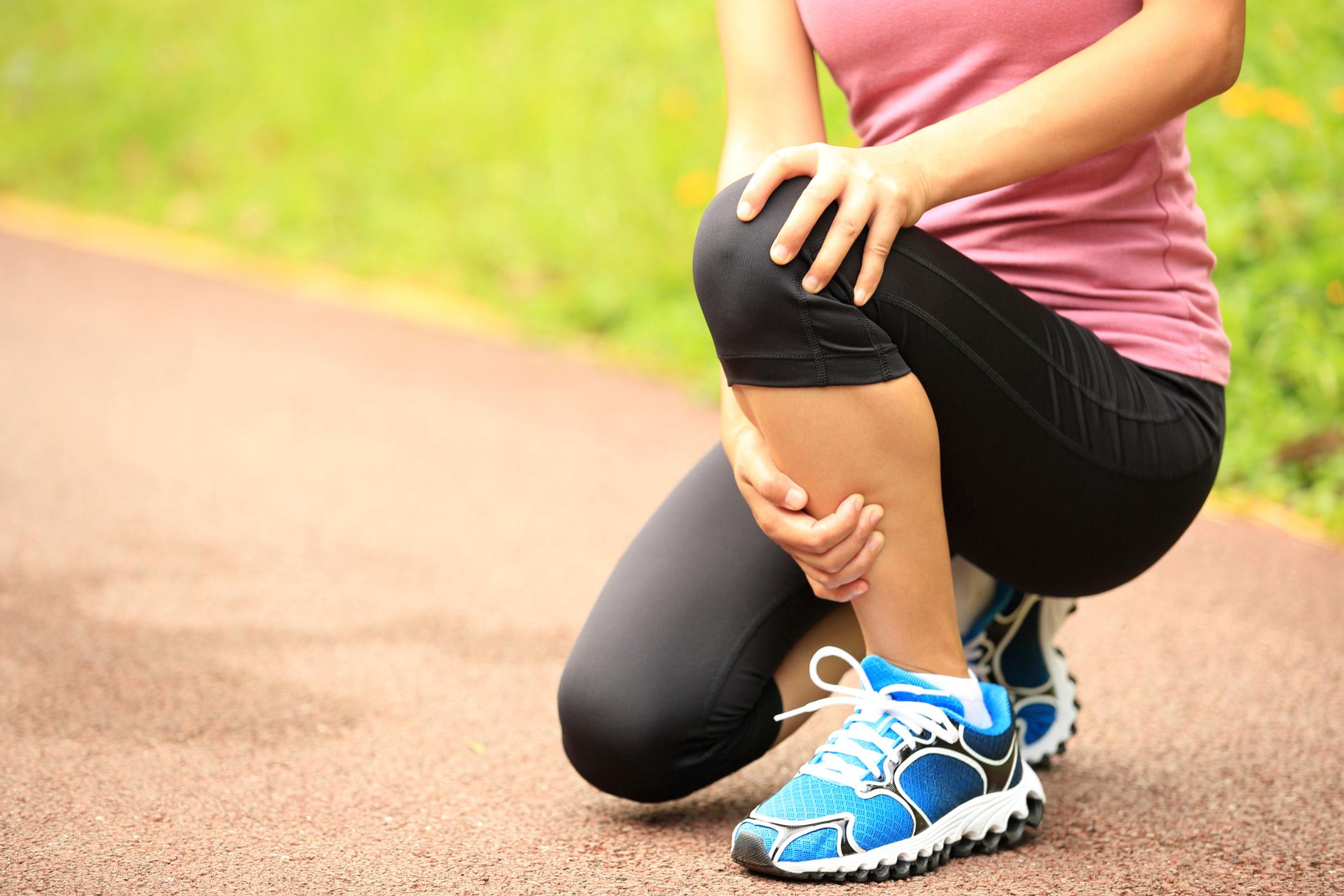 A woman crouching and holding her leg by her knee.