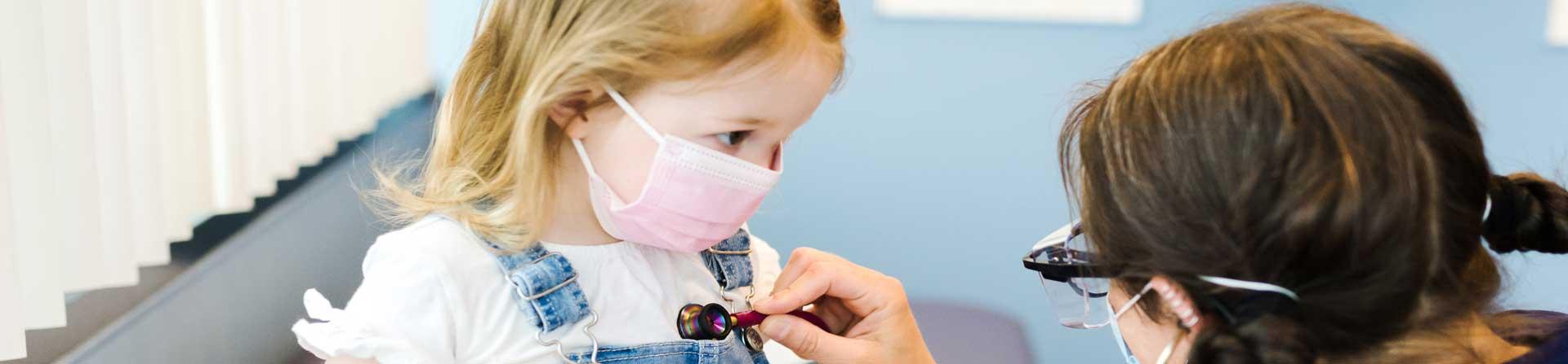 A healthcare provider listening to a young girl's breathing.