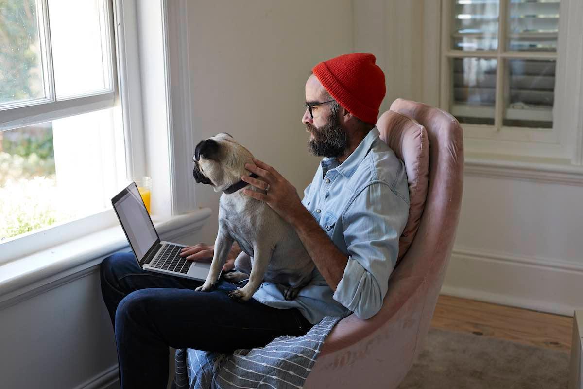 man working from home with dog on lap