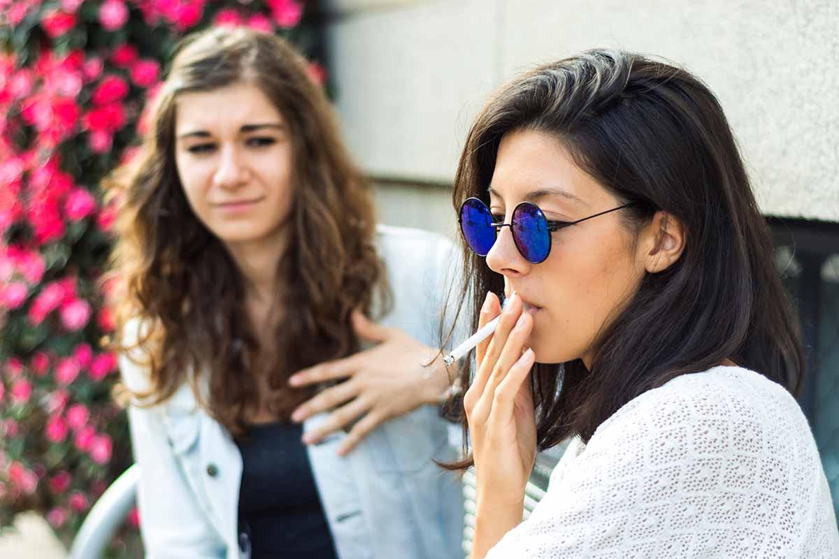 two people sitting together. one is smoking
