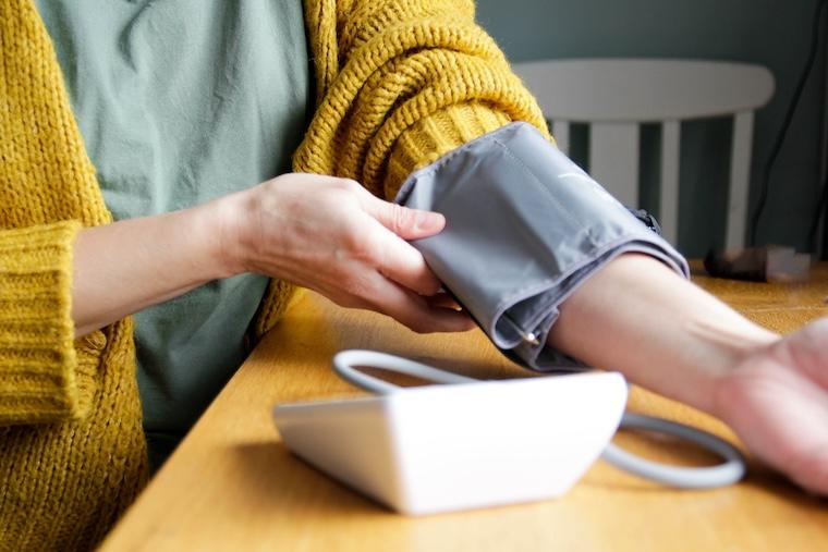 Woman pulls on blood pressure cuff at home