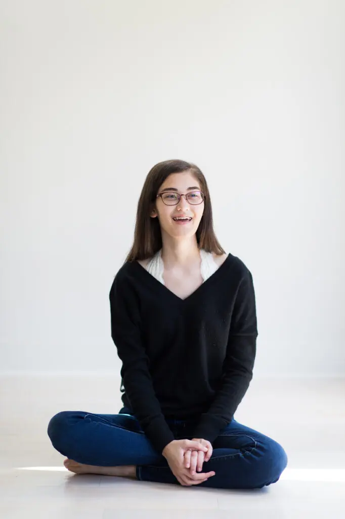 Madeline sits on floor and smiles