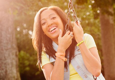 Tameka, a young heart transplant survivor, swings and smiles outside