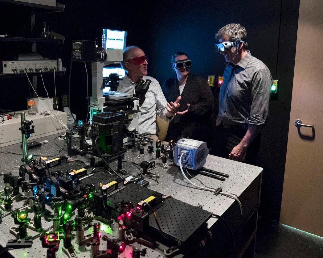 M. Mitchell Smith (from left), Margaret Grant and Dean H. Kedes have used this microscope Smith built to reveal how a cancer-causing virus clings to our DNA.