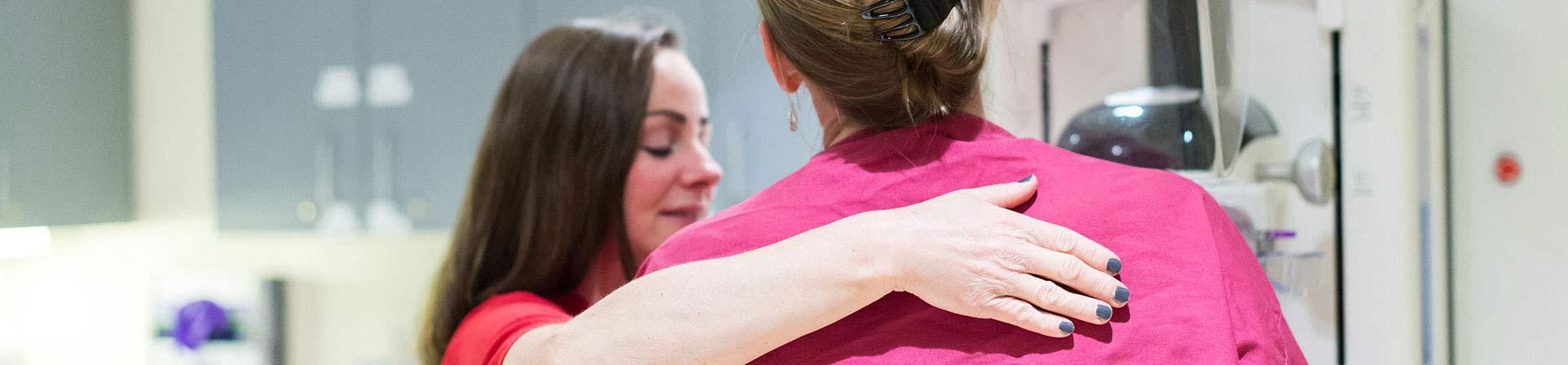 A healthcare provider guides a patient during a mammogram.