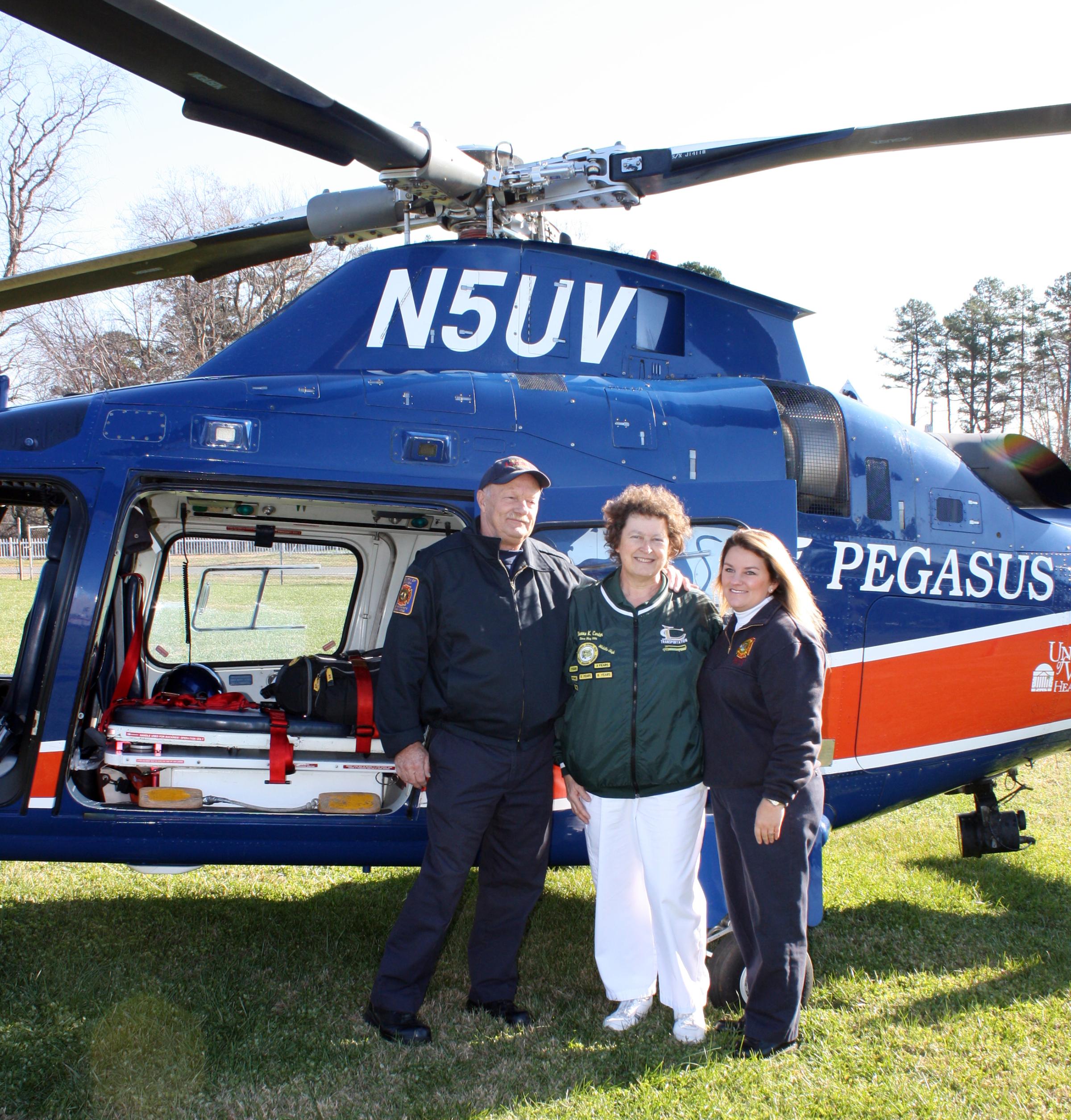 Eight days after suffering a serious heart attack, Dianna Carter (center) stands next to UVA's Pegasus helicopter with Louisa County Rescue Squad medics Buddy Hopkins and Kelly Staymates.