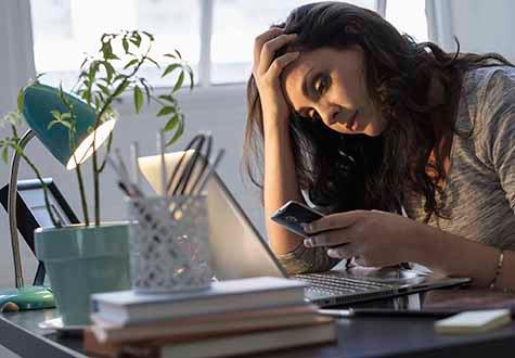 woman checking coronavirus news on her cell phone and laptop