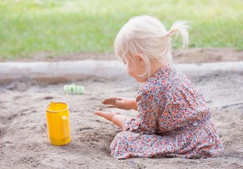 small girl playing in sandbox