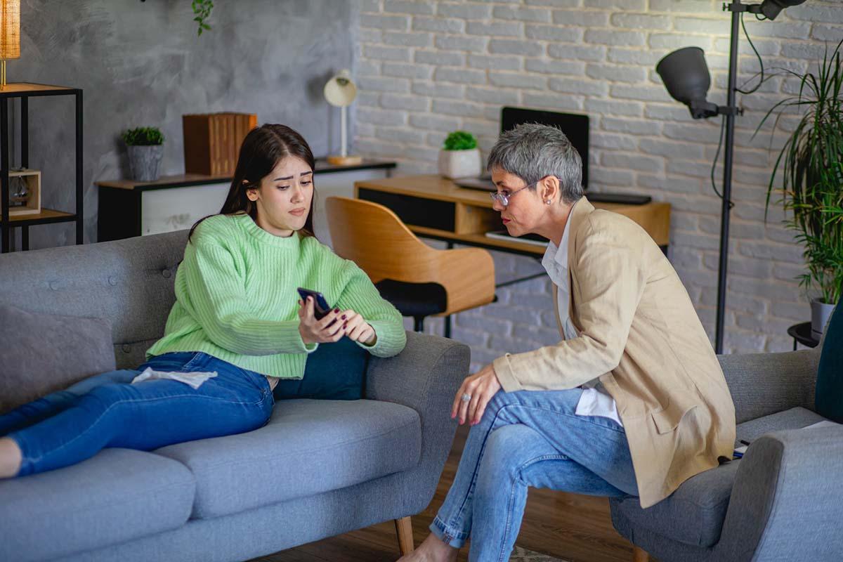 Teenager shows their cell phone to adult with concerned face
