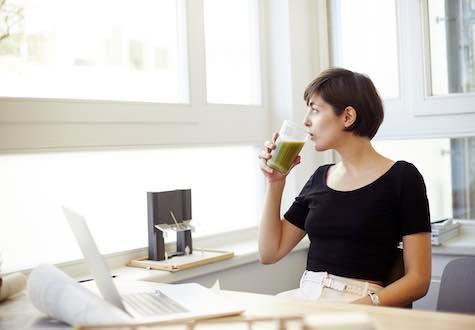 A woman taking a break to drink her smoothie to create a healthy workplace environment
