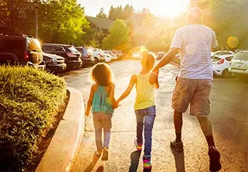dad and his 2 daughters walking across a parking lot