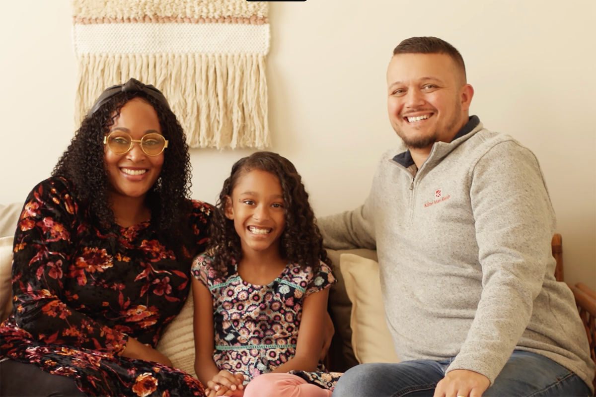 Faith sits between her two parents on the couch