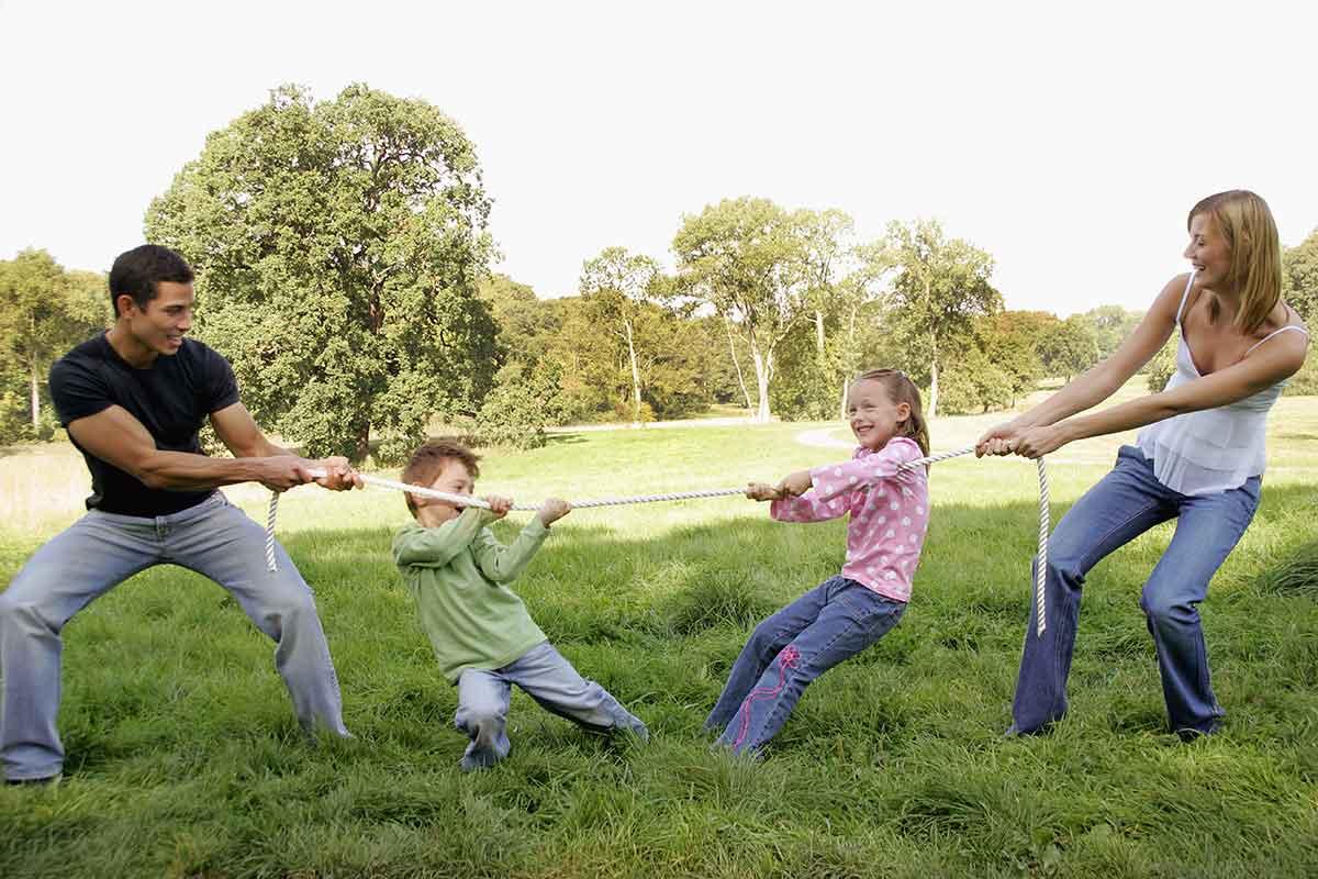 mom and dad keep their kids active with a tug-of-war game outside