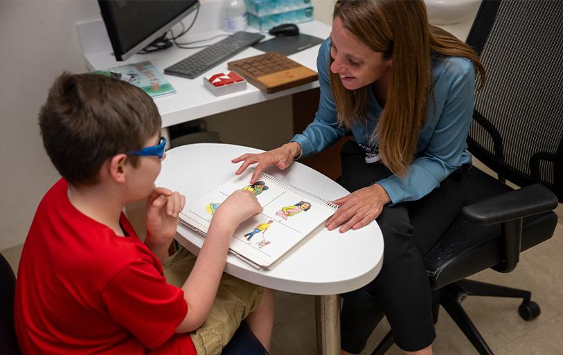 neuropsychologist helps child with communication aid