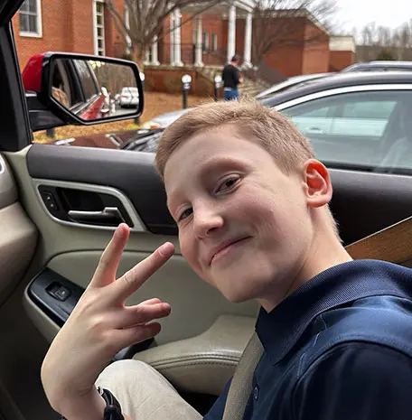 Benny holds up fingers in a peace sign while showing off the hair he's grown back