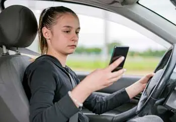 distracted driving teen looking at a phone while driving